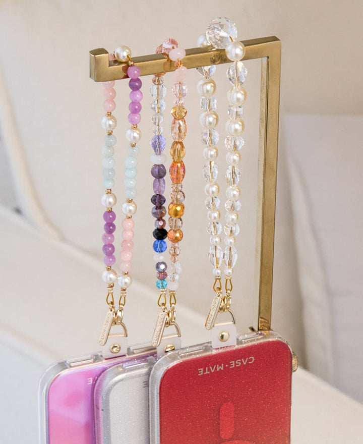 3 Phone Charms hanging from a stand with iPhones attached to them