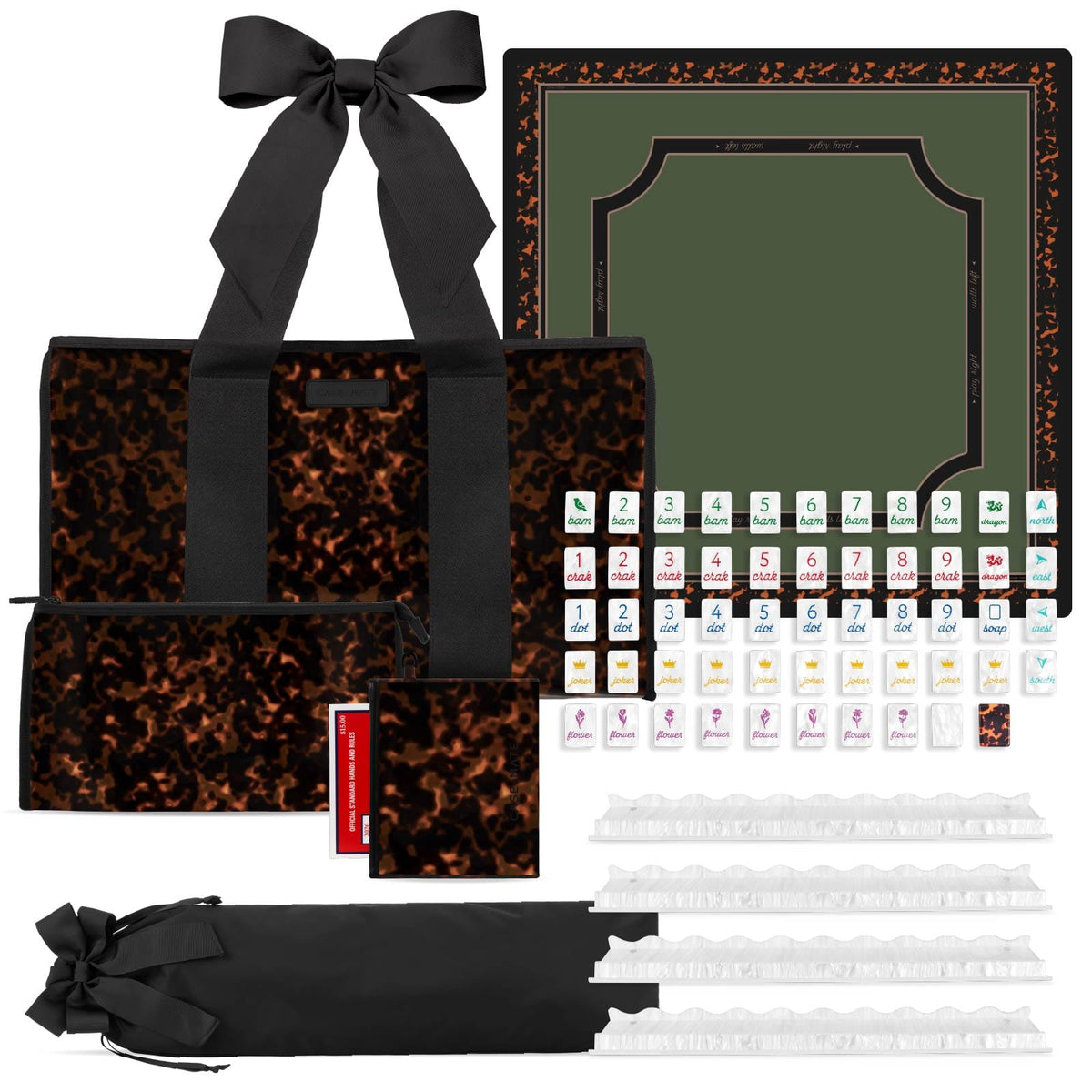 A mahjong set displayed on a white background, including a black-and-brown patterned tote bag with a large bow, a matching card holder, several small pouches, a black carrying strap, white tile racks, and a green playing mat with a black border and sample tiles arranged in rows.