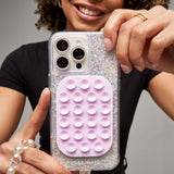 Person holding a phone case with a glittery exterior and pink bubble texture on a gray background
#color_stardust