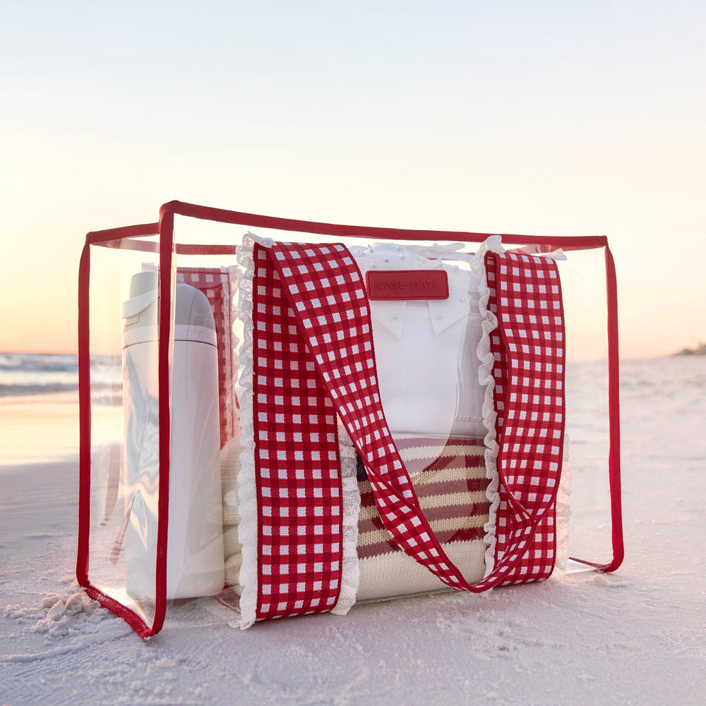 Clear beach bag with red checkered strap on a sandy beach
#color_cherry gingham