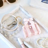 Pink keychain with a bow, pearl bracelet, and keys on a marble surface.
#color_ballet pink bow