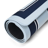 A rolled-up athletic mat with a navy blue and light blue striped pattern and white border details, showing a black textured underside.
#color_classic carolina blue