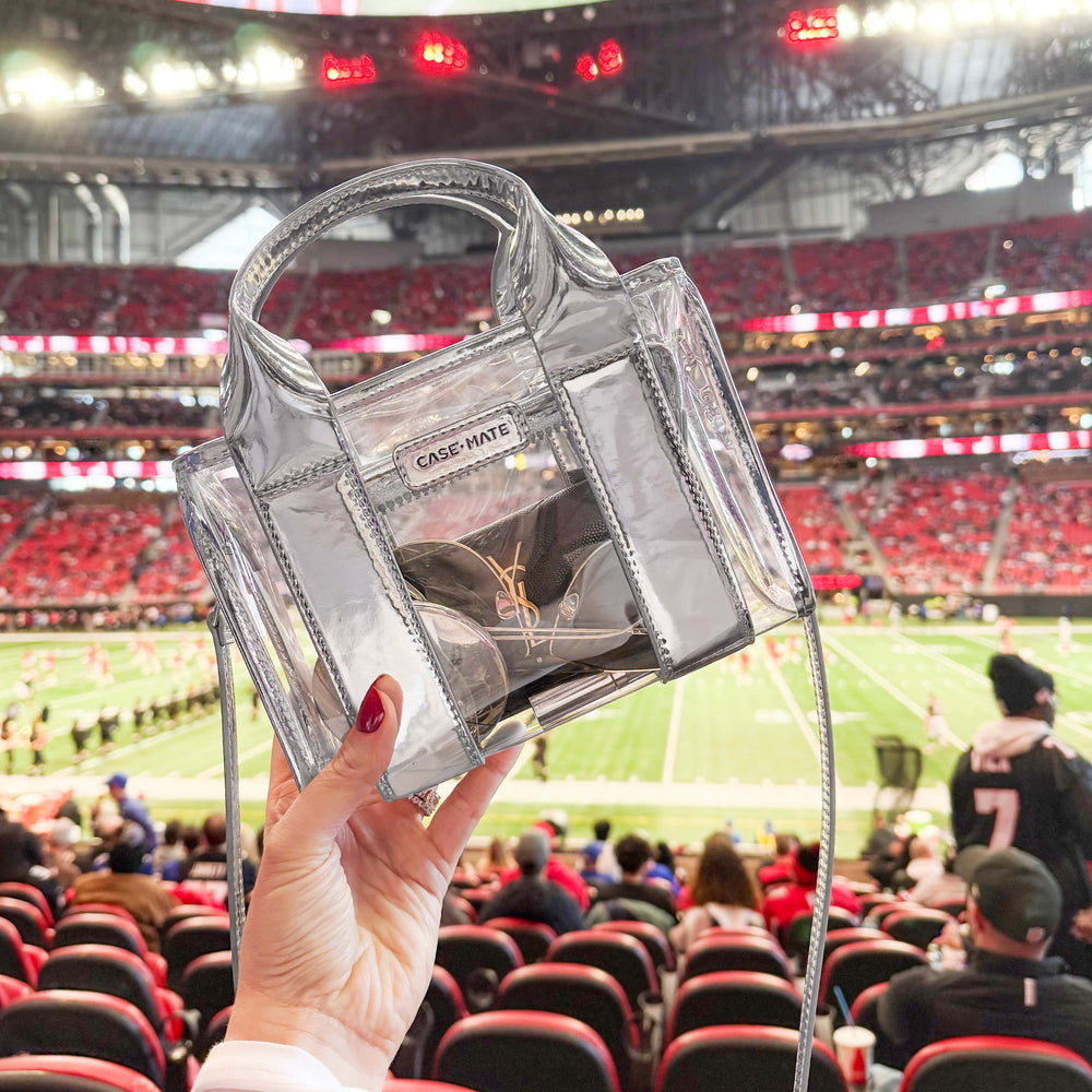 Clear handbag with 'CASE-MATE' branding held in front of a sports stadium.
#color_silver chrome