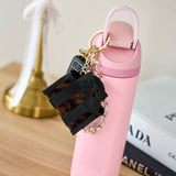 Black handbag charm on a pink water bottle with a blurred background
#color_tortoiseshell bow