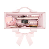 A light pink rectangular organizer case with a top handle and matching bow, shown open to reveal multiple interior compartments containing cosmetics and accessories, on a white background.
#color_ballet pink bow