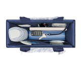 An overhead view of a navy blue organizer bag filled with various travel and household items, including a small white container, a blue zippered case, keys, a remote, and a hairbrush, on a white background.
#color_oxford navy