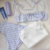 Blue and white checkered bikini set with a towel and sunscreen on a light background
#color_ivory pearl bow