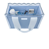 A light blue fabric storage tote bag with white handles, shown from a top-down view on a white background. The bag is filled with various small items, including a white bottle, a blue packet, and a white camera.
#color_carolina blue