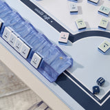 A close-up of a board game setup on a light tabletop, showing a translucent blue marble dice tray, white numbered tiles with blue and pink striped borders, and blue dice.
#color_carolina blue pearl