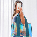 Person holding a transparent tote bag with colorful design, wearing headphones and taking a mirror selfie.
#color_emerald blue iridescent