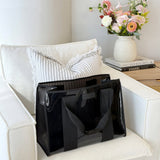 Black tote bag on a white couch with a vase of flowers and books in the background
#color_midnight black