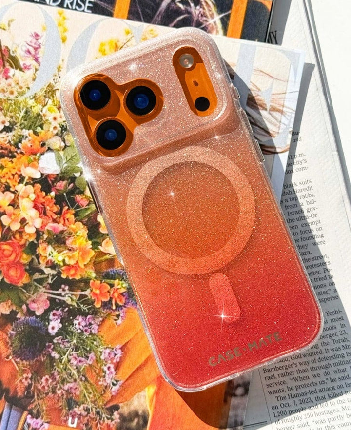 Orange iPhone 17 Pro Max Phone case with a orange gradient design laying on a floral and magazine background
