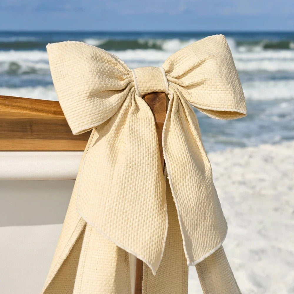 Beige bow on a chair with a beach background
#color_raffia bow