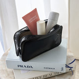 Black pouch with cosmetic items on top of a book Jelly Makeup Bag #color_midnight black