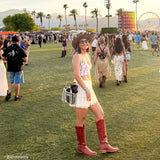Woman in cowboy boots and a hat at a music festival with palm trees and a Ferris wheel in the background. #color_silver chrome
