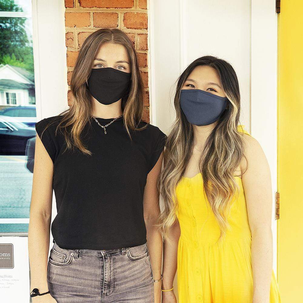 Woman wearing black cloth mask with other woman wearing navy cloth mask. color::Black