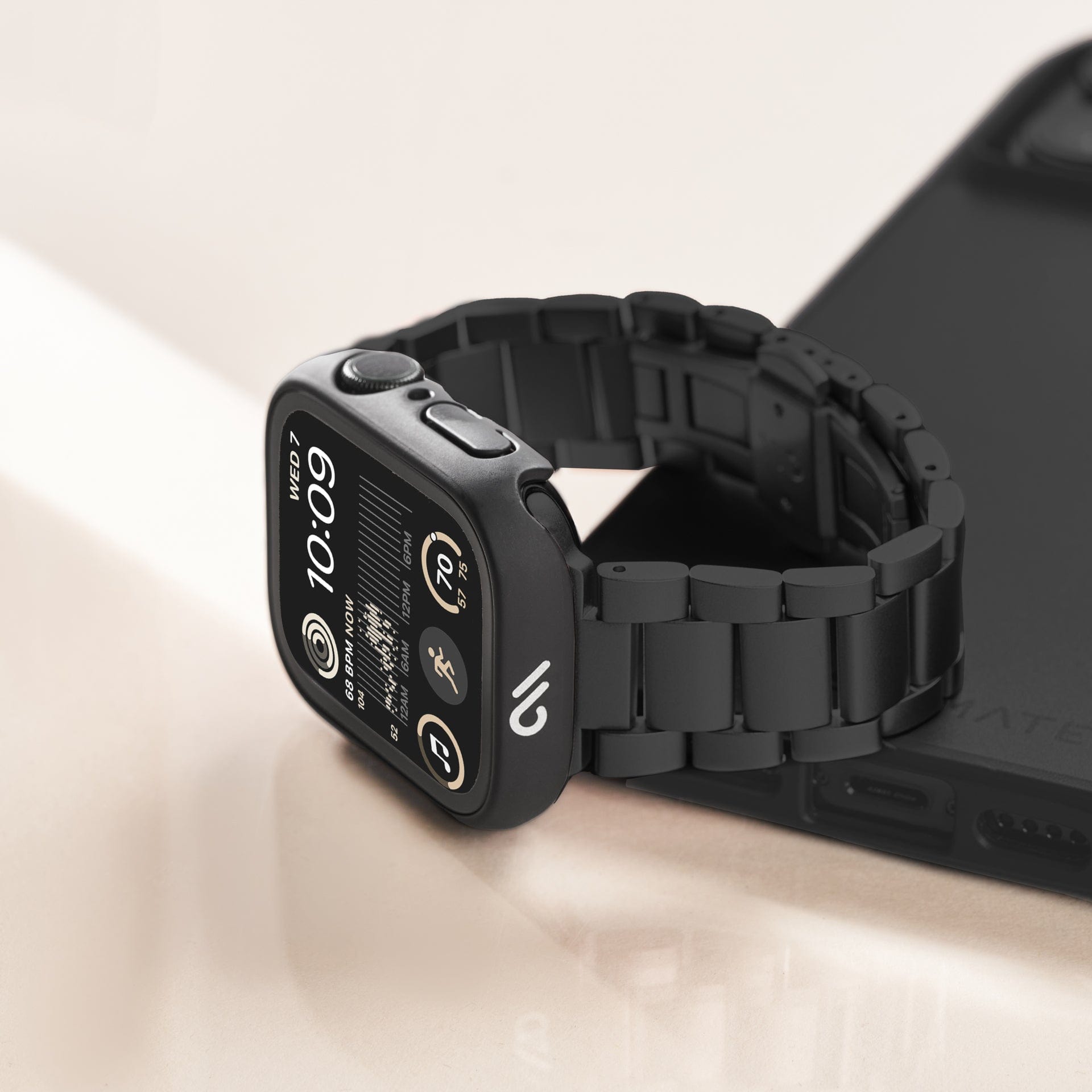 Apple Watch with tough black case and black link chain sitting on top of a phone.