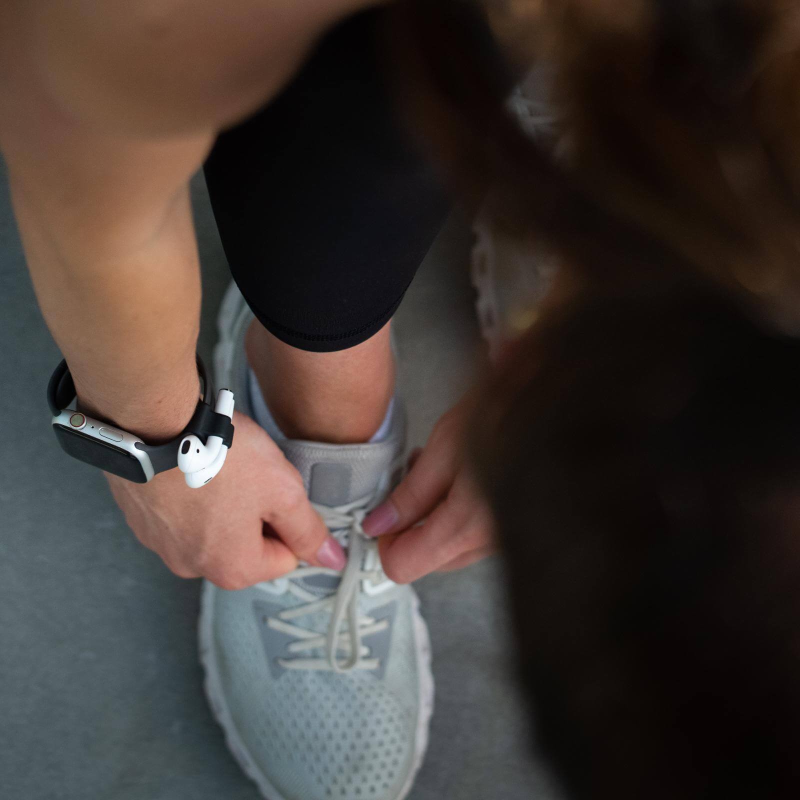 Tying shoes while wearing airpod watch band holder. color::Black