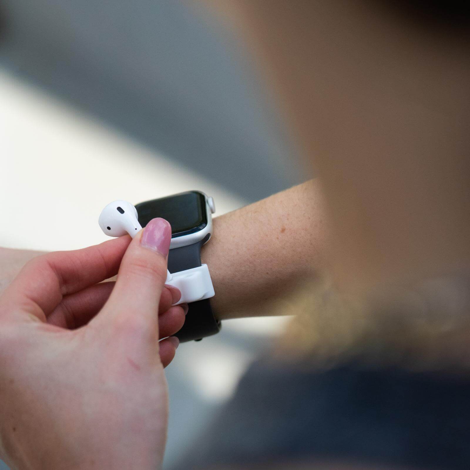 Hand placing AirPod into holder. color::White