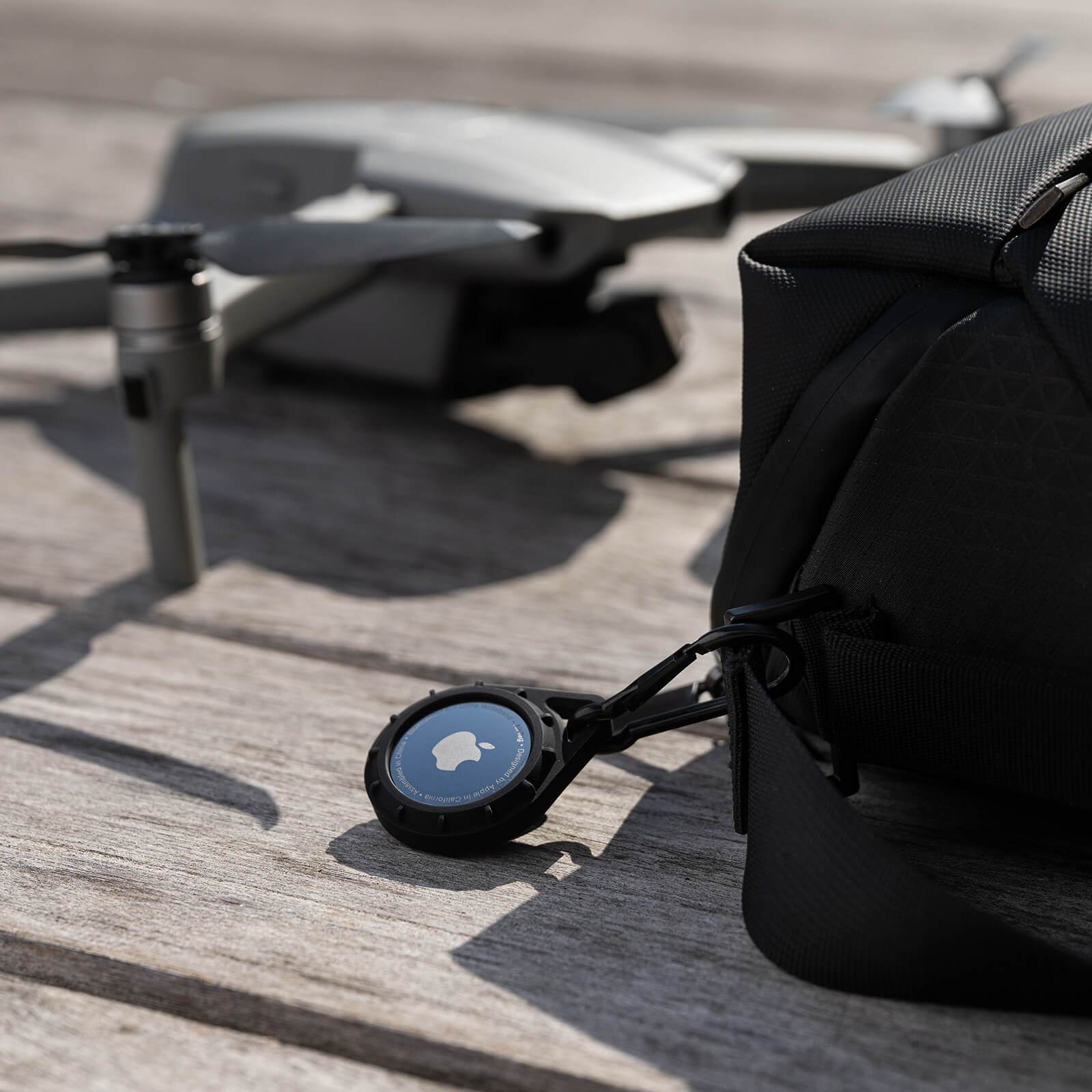 Pelican Protector AirTag Case clipped onto a backpack. color::Black