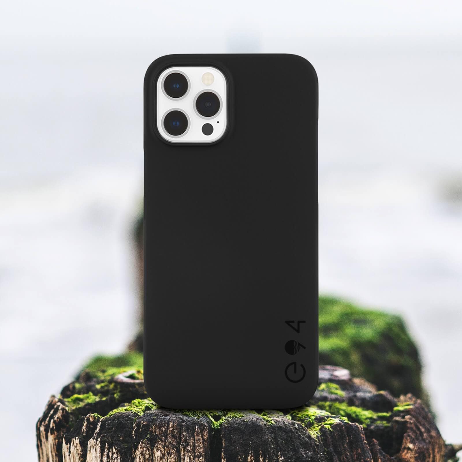 Black ECO 94 Barely There iPhone 12/12Pro case sitting on a log. color::Black