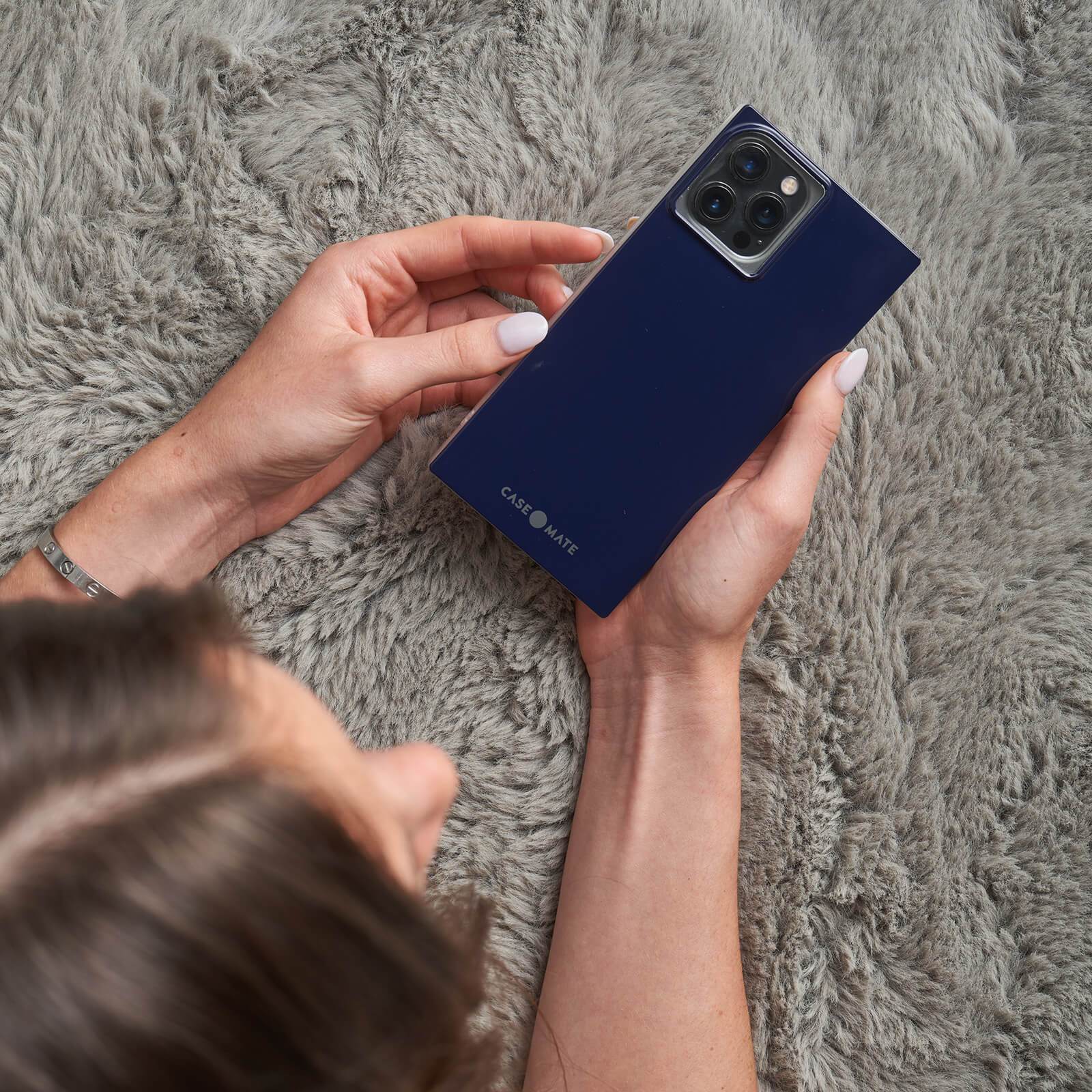 Hands holding dark blue square case. color::Navy