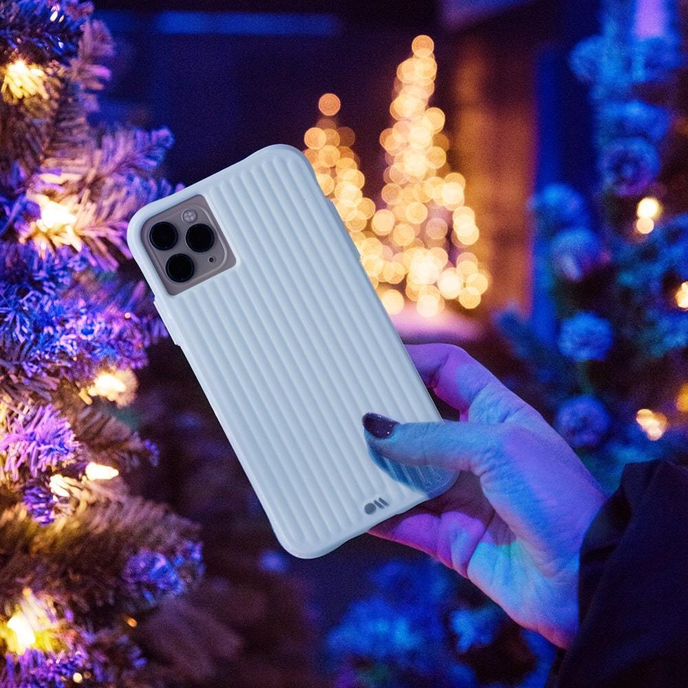 Hands holding white groove case in front of holiday tree.  color::Winter White