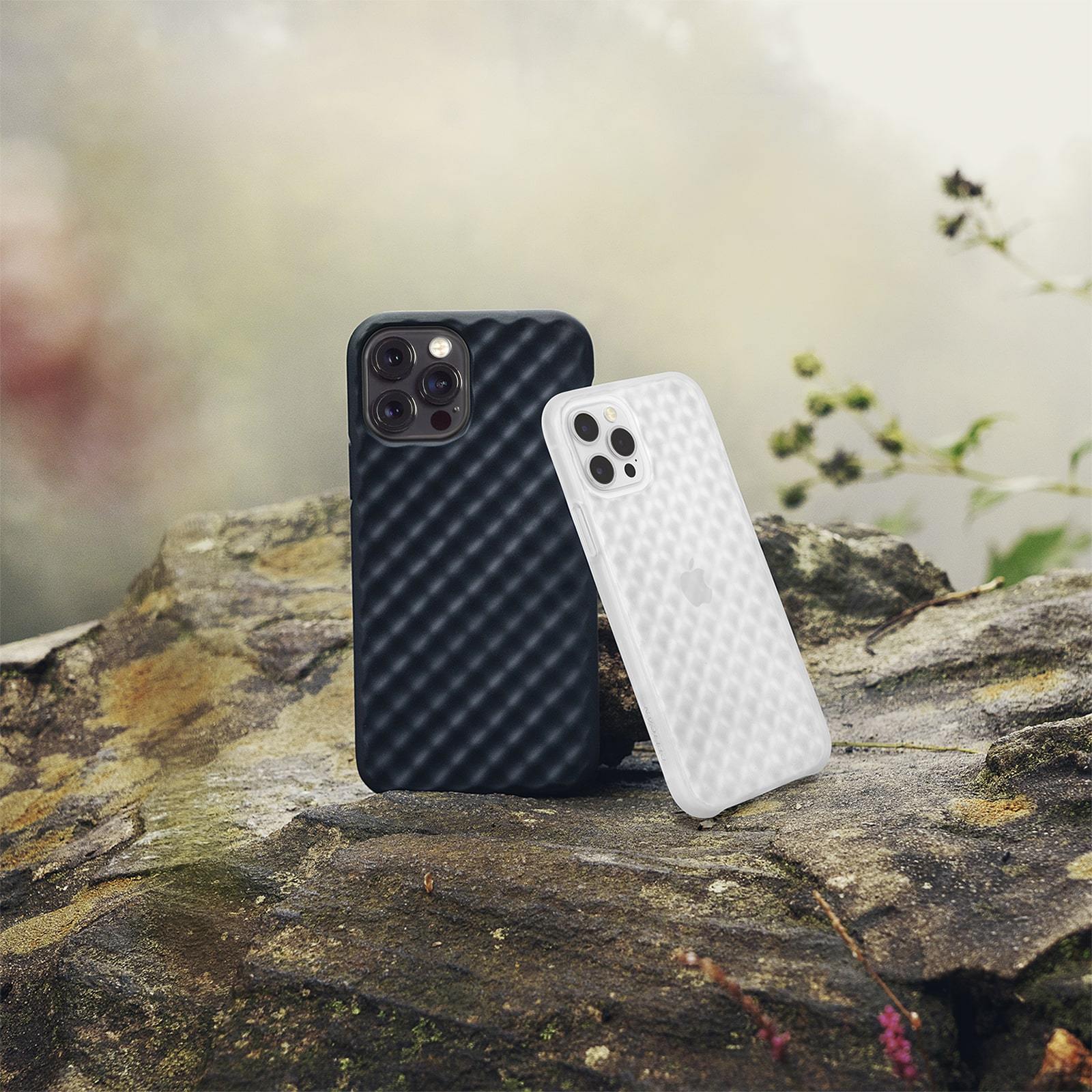 Black and Clear Pelican Rogue cases for iPhone 12 Pro Max leaning against each other in nature. color::Black