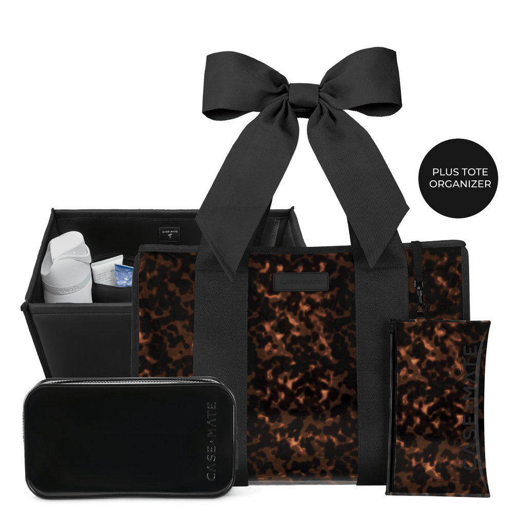 A black and leopard-print toiletry organizer set from Case Mate on a white background, featuring a large tote bag with a black ribbon handle, a black organizer bin, a black zip pouch with vertical branding, and a black hard case, with a circular badge reading 'PLUS TOTE ORGANIZER'.