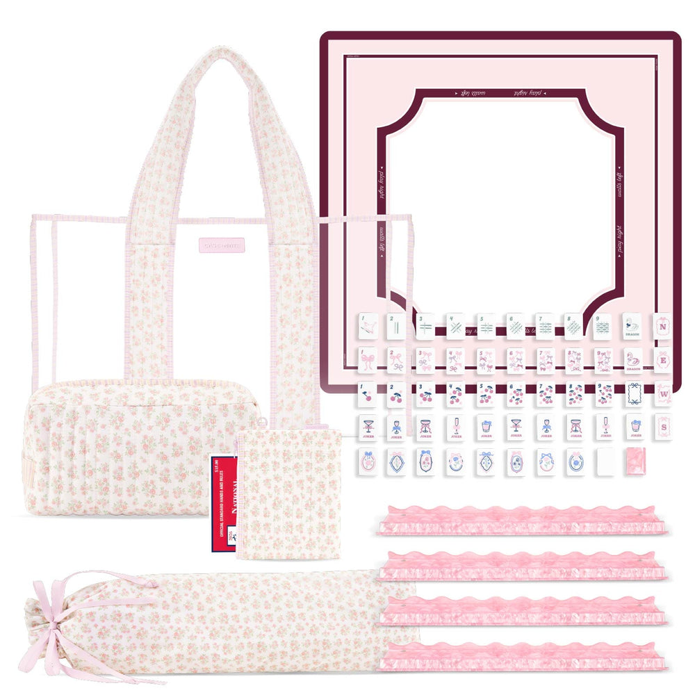 A pink and cream floral mahjong set displayed on a white background, including a carrying tote bag, a rectangular game board, a rack of white tiles, several pink scoring strips, and a rolled mat.