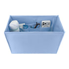 A light blue fabric organizer box with multiple interior pockets, shown on a white background and filled with assorted small items including a white bottle, a tube, glasses, and a white camera.

#color_carolina blue