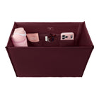 A burgundy fabric organizer pouch shown from above, filled with travel accessories including a pink water bottle, a phone case, a small card holder, and a white item. 
#color_mulberry