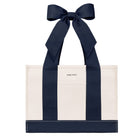 An off-white canvas tote bag with bold navy blue vertical stripes and matching navy ribbon handles tied in a large bow at the top. The brand name 'CASE-MATE' is printed in small black letters on the front pocket.
#color_oxford navy bow