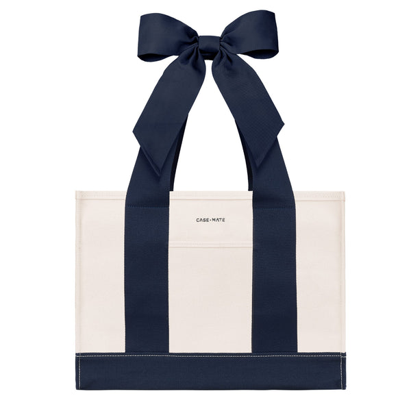 An off-white canvas tote bag with bold navy blue vertical stripes and matching navy ribbon handles tied in a large bow at the top. The brand name 'CASE-MATE' is printed in small black letters on the front pocket.
#color_oxford navy bow