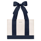 An off-white canvas tote bag with bold navy blue vertical stripes and matching navy ribbon handles tied in a large bow at the top. The brand name 'CASE-MATE' is printed in small black letters on the front pocket.
#color_oxford navy bow