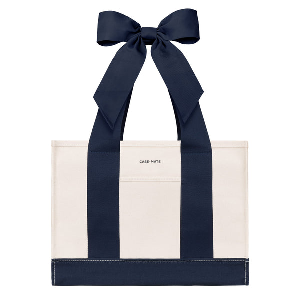 An off-white canvas tote bag with bold navy blue vertical stripes and matching navy ribbon handles tied in a large bow at the top. The brand name 'CASE-MATE' is printed in small black letters on the front pocket.
#color_oxford navy bow