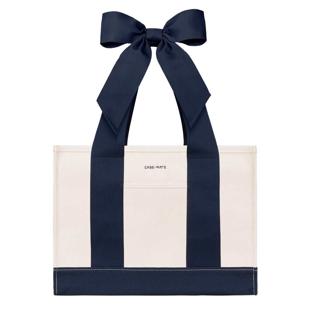 An off-white canvas tote bag with bold navy blue vertical stripes and matching navy ribbon handles tied in a large bow at the top. The brand name 'CASE-MATE' is printed in small black letters on the front pocket.
#color_oxford navy bow