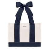 An off-white canvas tote bag with bold navy blue vertical stripes and matching navy ribbon handles tied in a large bow at the top. The brand name 'CASE-MATE' is printed in small black letters on the front pocket.
#color_oxford navy bow