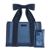 A dark blue denim strap jelly tote bag with matching denim shoulder straps and a large bow, shown alongside a matching translucent phone pouch on a plain white background.
#color_dark wash denim bow