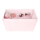 A light pink fabric organizer box with multiple interior pockets, shown holding a pink bottle, a small pink container labeled Summer Brights, a pair of glasses, and a pink phone case on a white background.

#color_ballet pink