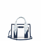 A Case-Mate structured handbag with navy blue and white vertical stripes, featuring a light blue and white floral silk scarf tied to the top handle, set against a plain white background.

#color_something navy twilly