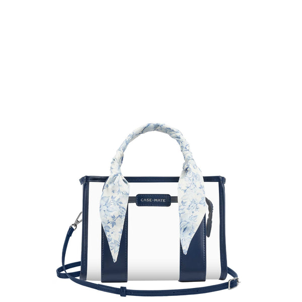 A Case-Mate structured handbag with navy blue and white vertical stripes, featuring a light blue and white floral silk scarf tied to the top handle, set against a plain white background.

#color_something navy twilly