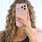 Person holding a pink phone with a matching case against a white background