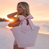 Woman holding a pink tote bag with a bow on a beach at sunset #color_ballet pink bow