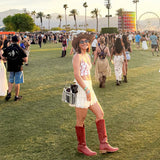 Woman in cowboy boots and hat at a music festival with palm trees and Ferris wheel in the background.

#color_silver chrome
