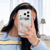 Person holding a phone with a clear case featuring Guerlain branding. #color_twinkle