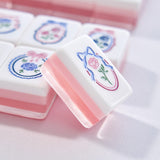 A close-up of a pink and white mahjong tile with a floral crest design, set against a matching pink and white background of other tiles.
#color_ballet pink pearl edition