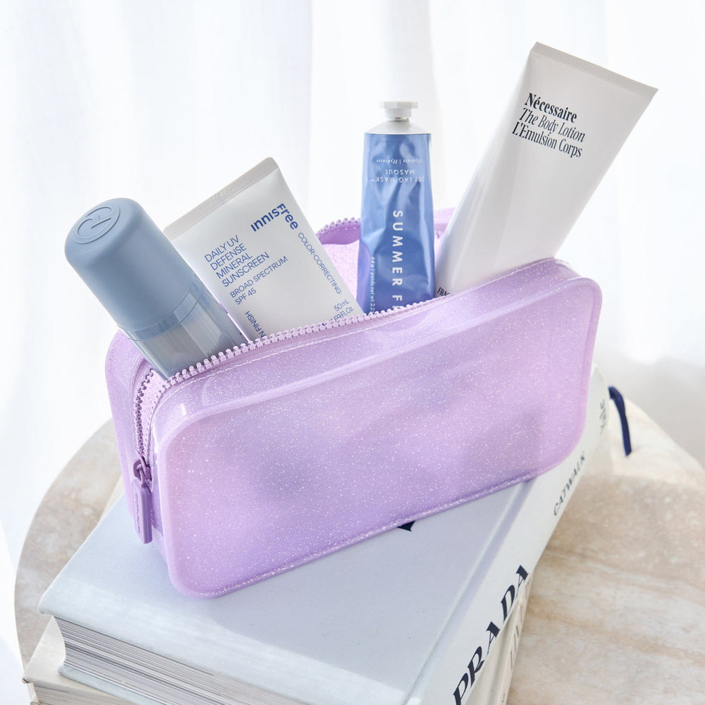 Purple cosmetic bag with skincare products on a white surface