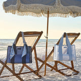 Beach chairs with two jelly tote bags and an umbrella on a sandy beach