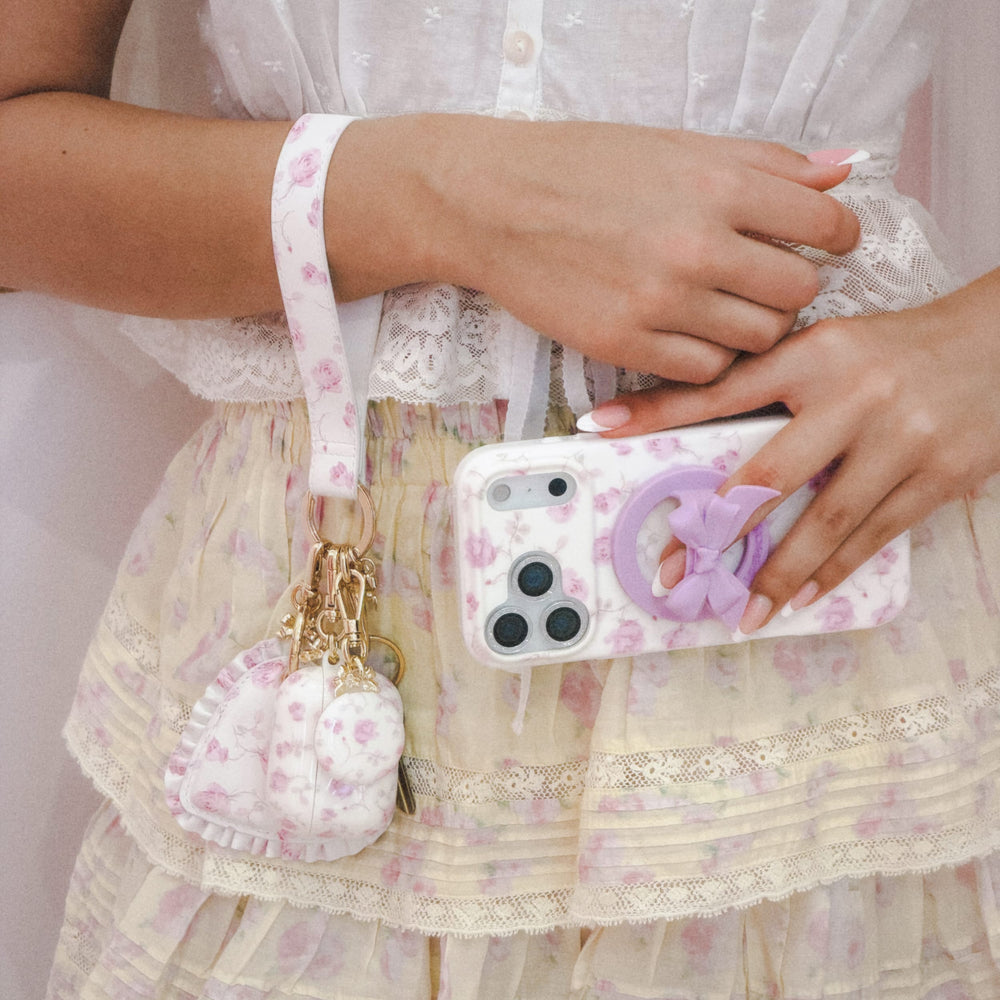 Person holding a phone with a floral case and matching pouch, wearing a white lace dress.
#color_blooming heirloom
